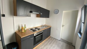A compact kitchen with a gas stove, oven, and a sink. There are cabinets above the counter, and a clock on the wall. - Modern & central in the cityI 8 guests I kitchen I washing machine I balcony (Stuttgart)