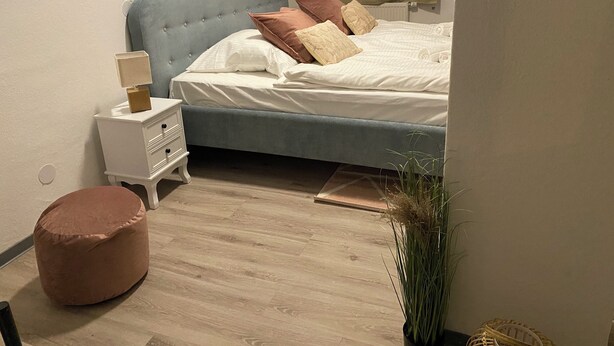 Ein Schlafzimmer mit einem Bett, einem Nachttisch und einem kleinen, runden Hocker.