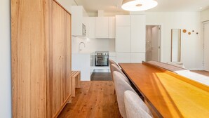 Una cocina moderna con armarios blancos, un banco de madera y una lámpara colgante.