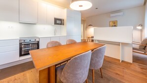 Een moderne keuken met witte kasten, een houten eettafel en grijze stoelen.