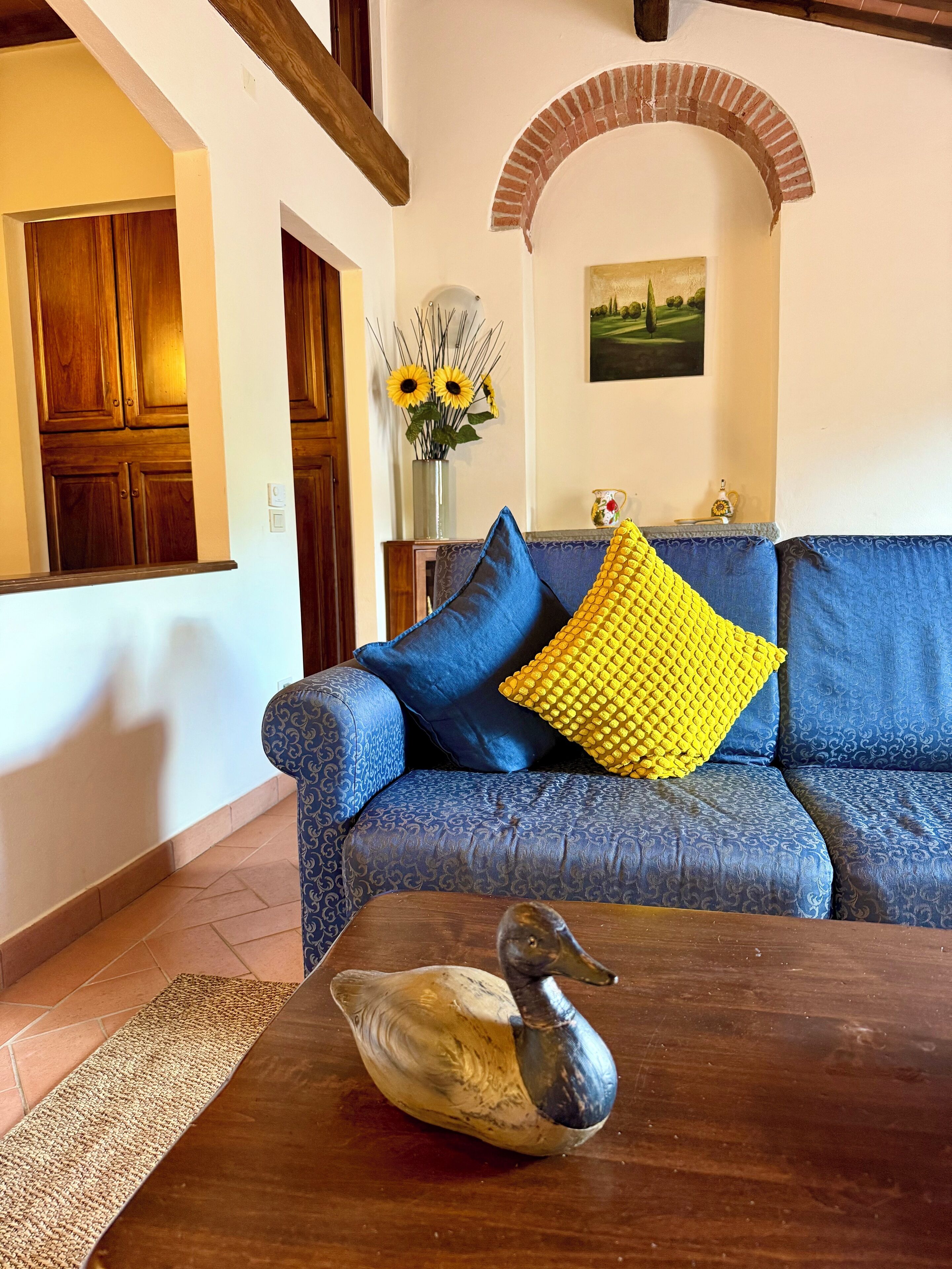 Uma sala de estar com um sofá azul, uma mesa de centro de madeira e um pato decorativo.