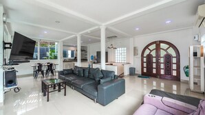 A spacious living room with a grey sofa, a coffee table, and a TV mounted on the wall. - 4BR PoolVilla and SeaView V199 (Patong)