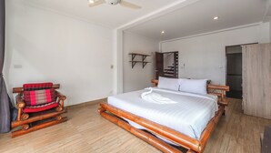 A bedroom with a wooden bed, a ceiling fan, a wardrobe, and a small seating area. - 4BR PoolVilla and SeaView V199 (Patong)