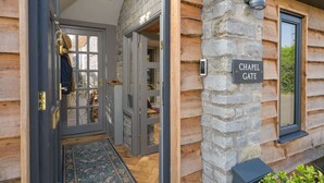 Une cabane en rondins avec une façade en pierre, une porte d’entrée en verre et une enseigne indiquant « CHAPEL GATE ».