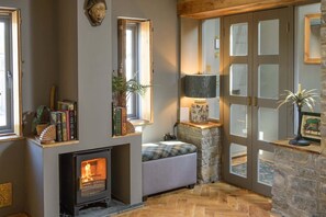 A cozy room with a fireplace, a sofa, and a stone wall with windows.