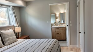 A bedroom with a bed, a nightstand, a dresser, and a mirror.
