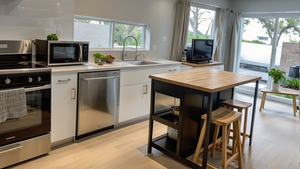 A modern kitchen with stainless steel appliances, a wooden dining table, and a TV.