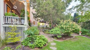 A house with a covered porch, a garden with various plants, and a wooden fence. - < 1 Mi to Dtwn Salem: Apt w/ Shared Patio & Yard! (Salem)
