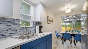 Una cocina moderna con armarios azules, un lavamanos doble y una zona de comedor con sillas azules.