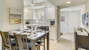 A modern kitchen with white cabinets, a dining table with chairs, and a kitchen island. - Golf & Swim: Country Club Condo in Palm Desert (Palm Desert)