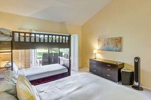 Une chambre avec un lit superposé, un bureau, une commode et un tableau accroché au mur.