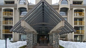 Een hotel met een opvallende driehoekige entree, meerdere balkons en een stenen gevel.