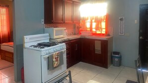 A kitchen with a stove, microwave, and dark wooden cabinets. - Relaxing, family-friendly 2-bedroom apartment with A/C, WiFi & Central Location (Golconda)