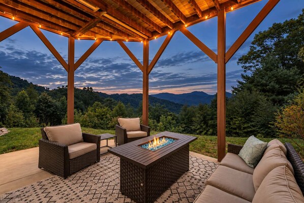 An outdoor patio with a fire pit, seating, and a view of the mountains.