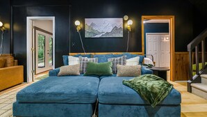 A modern bedroom with a large bed, a painting above the bed, and a staircase to the right.
