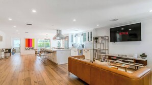 A modern living space with a kitchen, dining area, and a large TV mounted on the wall.