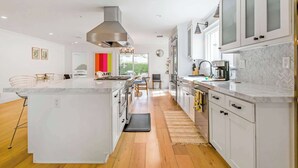 A modern kitchen with white cabinetry, a large island, and a view to the outside.