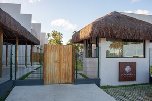 A villa with a thatched roof, a wooden gate, and a sign for 'manah Villas Boutique'. - Condomínio Manah (São Miguel dos Milagres)
