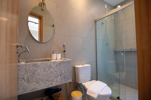 A modern bathroom with a granite sink, a toilet, and a glass-enclosed shower. - Condomínio Manah (São Miguel dos Milagres)
