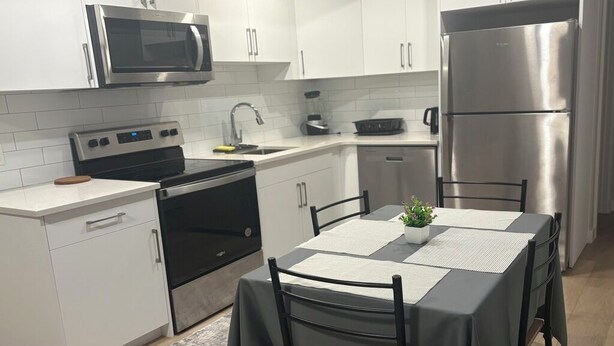 A modern kitchen with white cabinetry, a stainless steel refrigerator, a microwave, and a stove. - Elegant 2-Bed 2-Bath SE Calgary, fully furnished near amenities, mid-term, ready (Calgary)