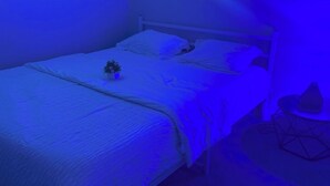 A bedroom with a bed, pillows, a small plant, and a geometric-patterned side table. - Elegant 2-Bed 2-Bath SE Calgary, fully furnished near amenities, mid-term, ready (Calgary)
