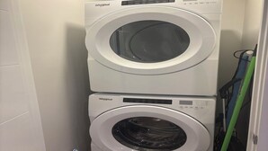 A stacked washer and dryer unit in a small laundry room. - Elegant 2-Bed 2-Bath SE Calgary, fully furnished near amenities, mid-term, ready (Calgary)