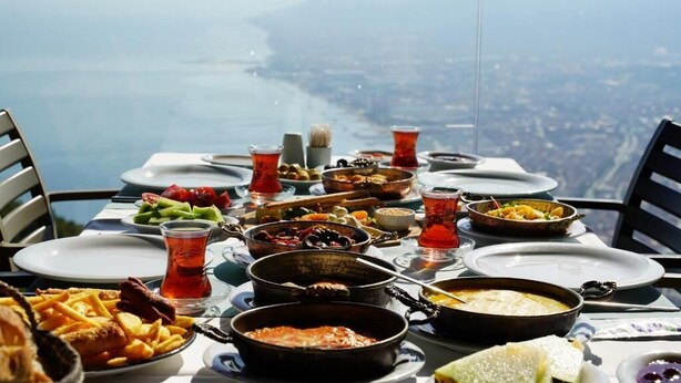 Une table dressée avec différents plats et boissons, offrant une vue panoramique sur une côte pittoresque.