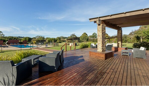 Terraza de madera con asientos exteriores y una estructura de pilar de piedra.
