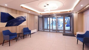 A modern lobby with a large abstract painting, blue seating, and a glass door leading outside. - Landmark Hotel Erdenet (Erdenet)