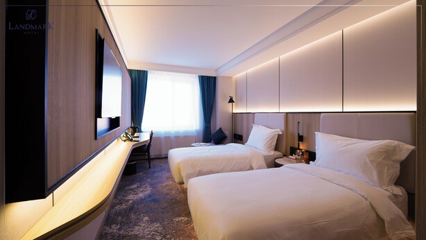A hotel room with two beds, a desk, a chair, a TV, and a large mirror. - Landmark Hotel Erdenet (Erdenet)