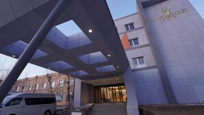 The exterior of the Landmark Hotel with a modern architectural design, featuring a prominent entrance and a van parked outside. - Landmark Hotel Erdenet (Erdenet)