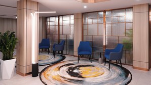 A modern interior with a seating area featuring blue chairs, a large abstract rug, and a potted plant. - Landmark Hotel Erdenet (Erdenet)