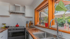Une cuisine avec des carreaux blancs, des appareils en acier inoxydable et une fenêtre donnant sur un paysage verdoyant.