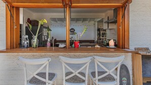 Une cuisine avec un comptoir en bois, deux chaises blanches et une vue sur la salle à manger.