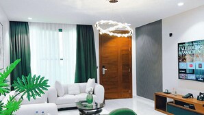 Un soggiorno moderno con un divano bianco, una poltrona verde, un tavolino rotondo e una TV a parete.