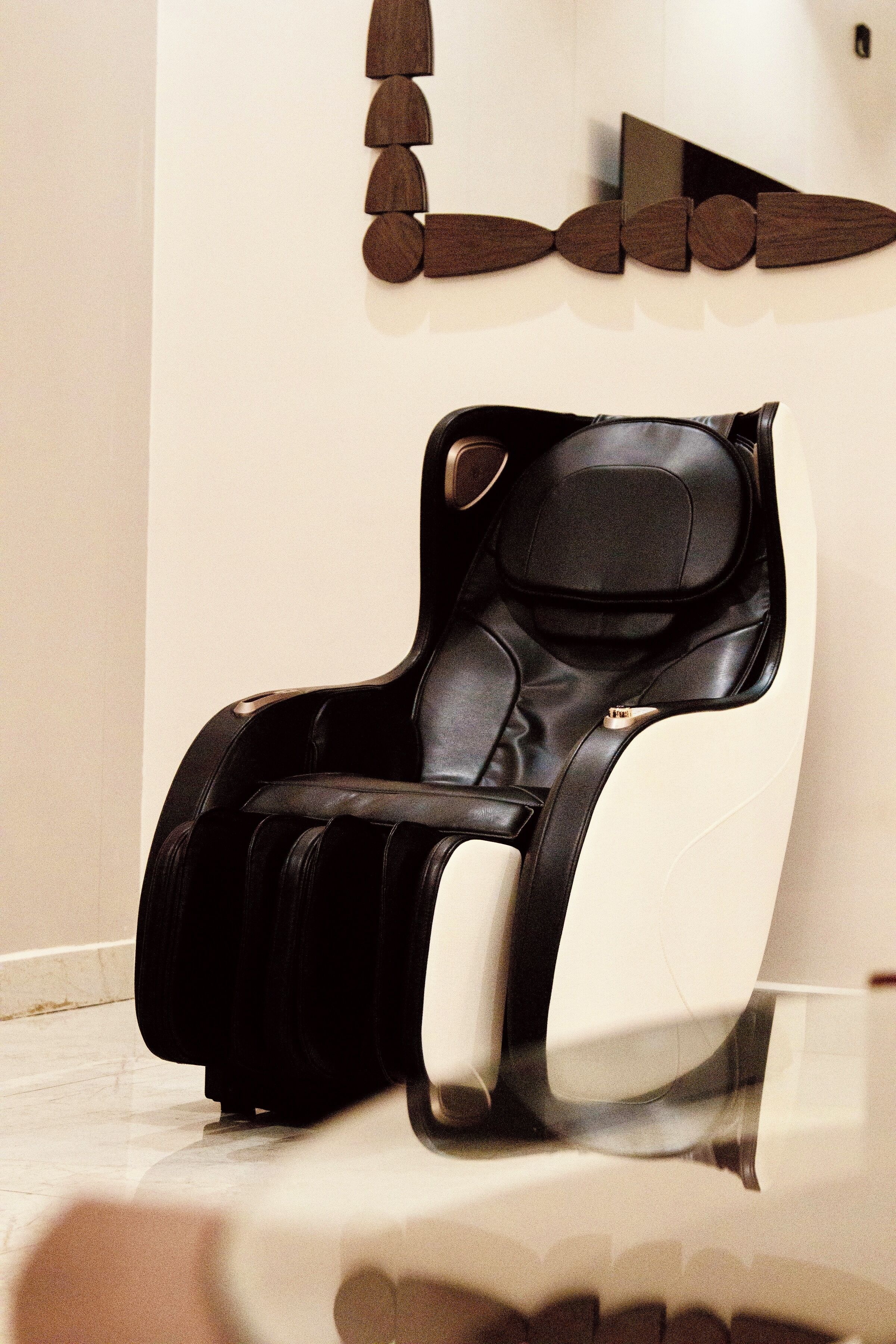 A massage chair in a room with a white wall and a geometric wall decoration.