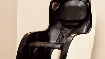 A massage chair in a room with a white wall and a geometric wall decoration.