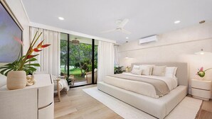 A modern bedroom with a large bed, a desk, and a view of greenery outside. - Kaia Villa, at Turtle Bay - Modern North Shore Oahu Retreat w/Lanai & Golf Views (Kahuku)