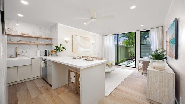 A modern kitchen with a central island, built-in shelves, and a large window offering a view of the outdoors. - Kaia Villa, at Turtle Bay - Modern North Shore Oahu Retreat w/Lanai & Golf Views (Kahuku)