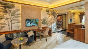 A modern living room with a sofa, a dining table, and a TV. - The Grand (Thekkady)