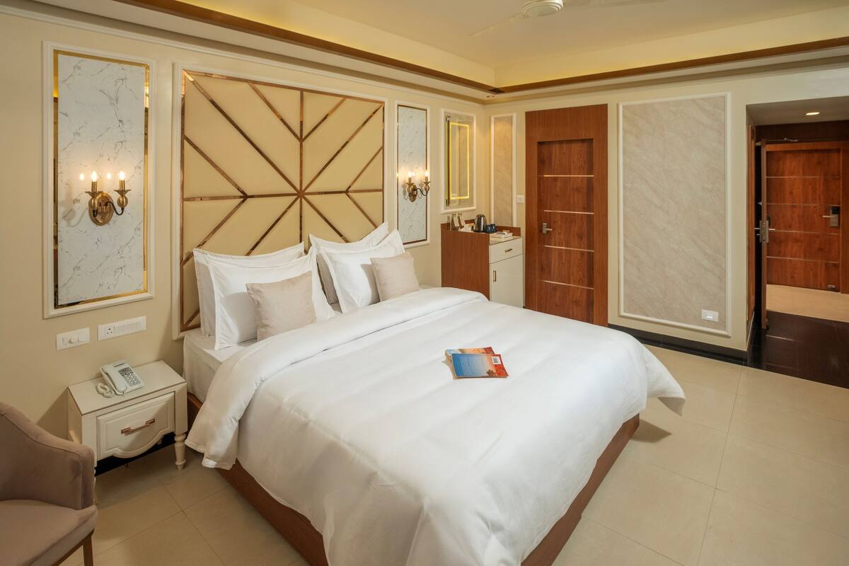 A hotel room with a large bed, bedside tables, a wardrobe, and a mirror.