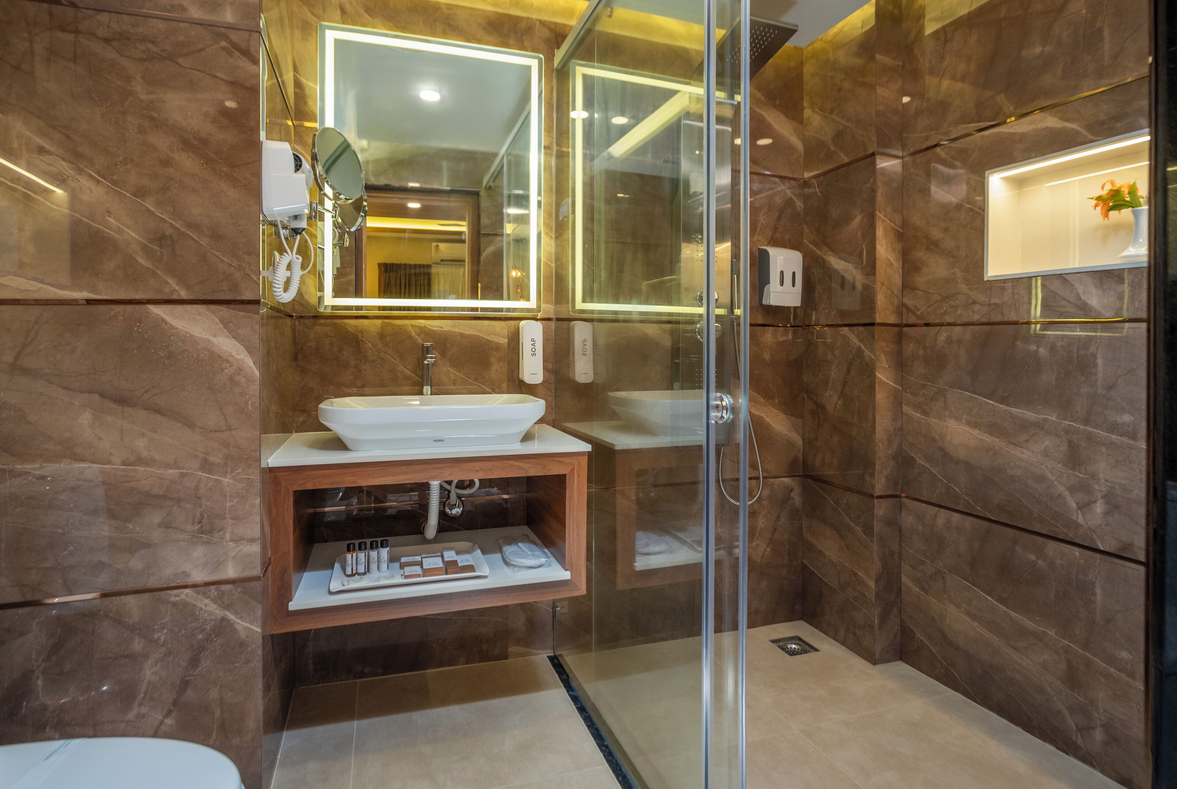 Une salle de bain moderne avec une douche à parois de verre, un meuble-lavabo en marbre et un grand miroir.