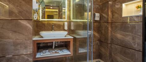 A modern bathroom with a glass-enclosed shower, a marble vanity, and a large mirror.