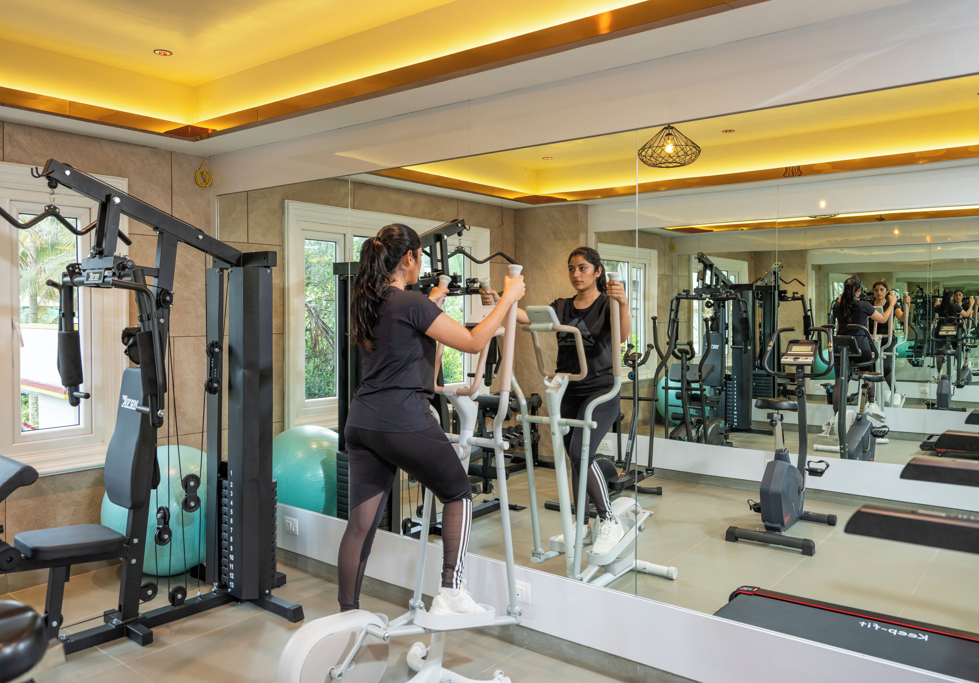 Un gimnasio con equipo de ejercicio, un espejo y una cinta de correr.