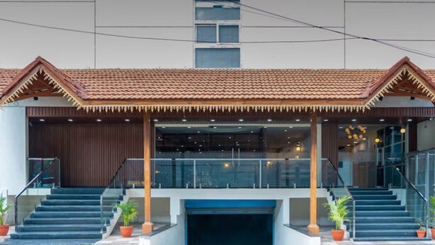 A modern building with a covered entrance, a staircase, and potted plants. - VITS SELECT BENGALURU (Bengaluru)