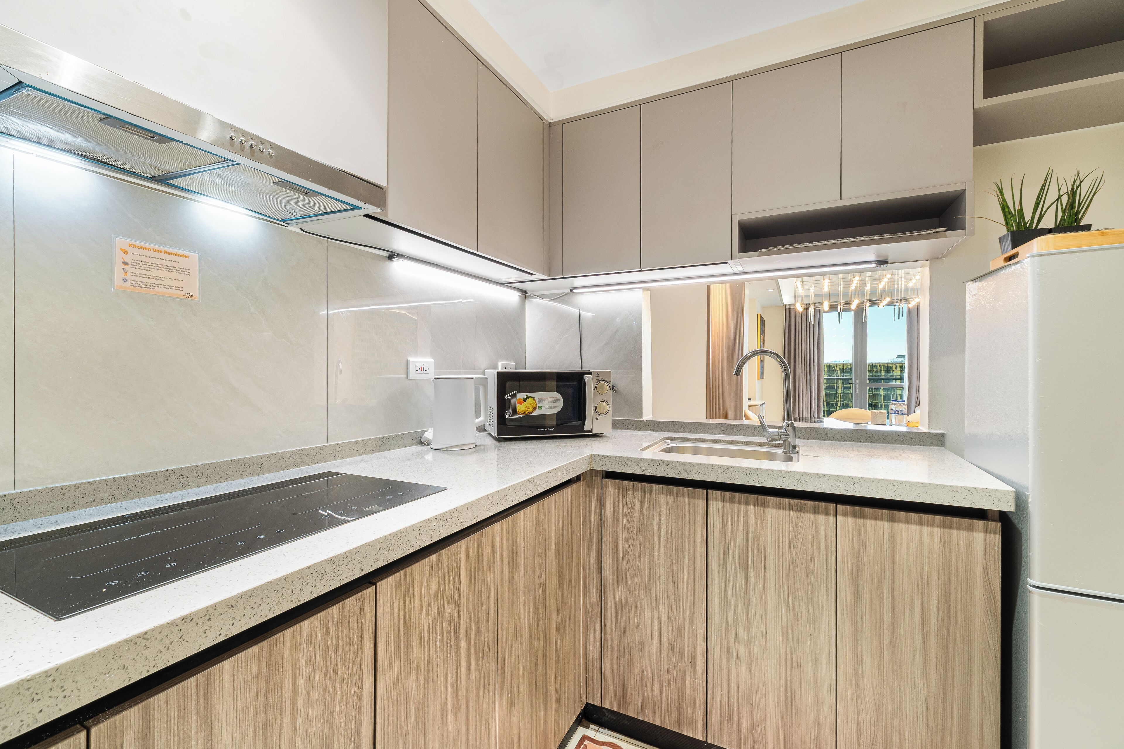 A modern kitchen with a built-in microwave, a stainless steel range hood, and a granite countertop.