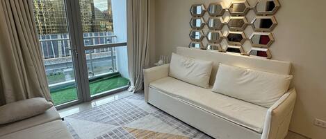 A modern living room with a white sofa, a large chandelier, and a geometric-patterned rug.