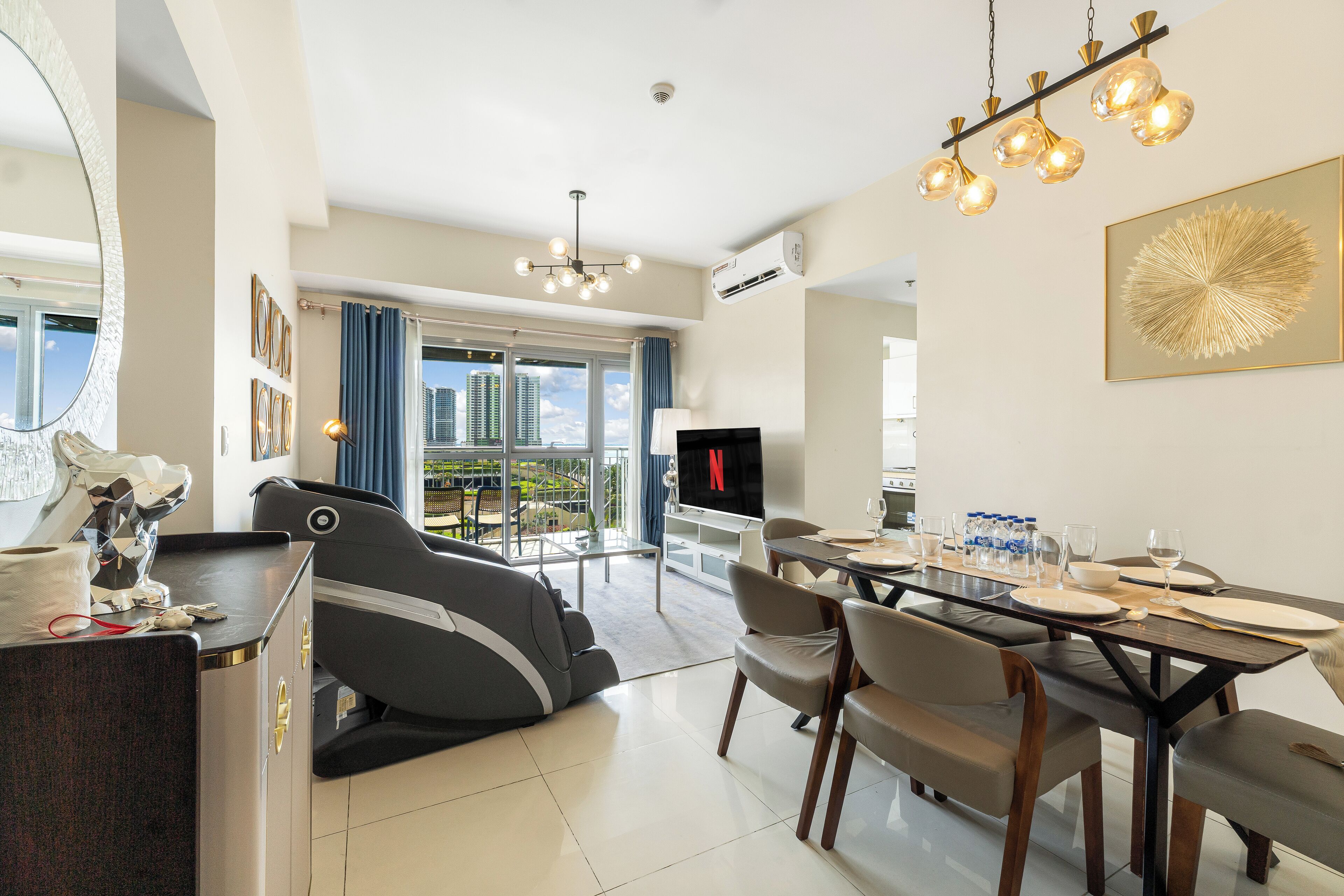 A modern living room with a dining area, a massage chair, and a TV.