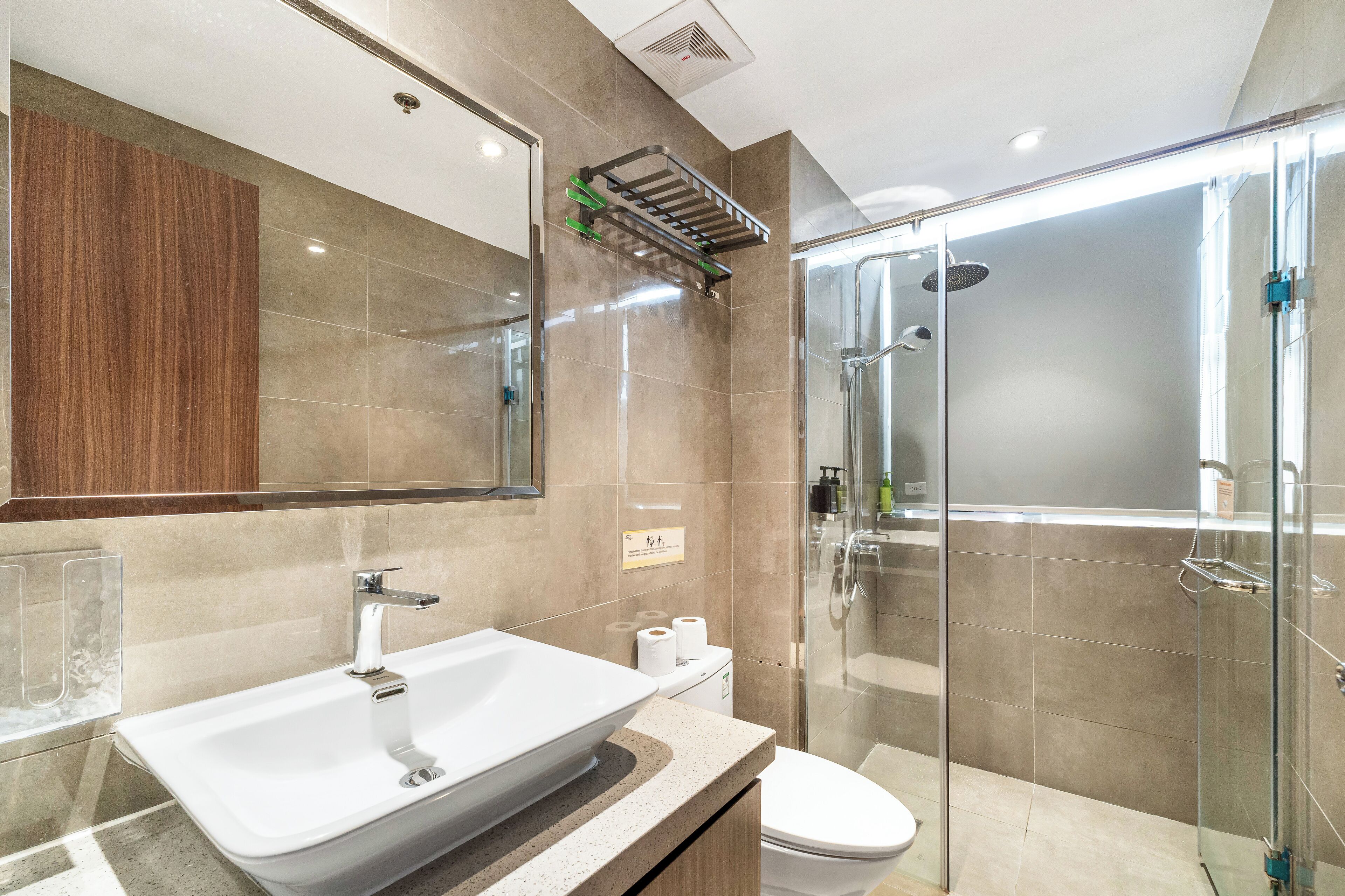 A modern bathroom with a large sink, toilet, and glass shower enclosure.