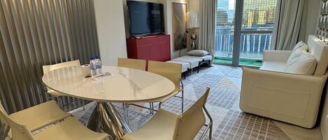 A modern hotel room with a dining area, a sofa, and a TV.
